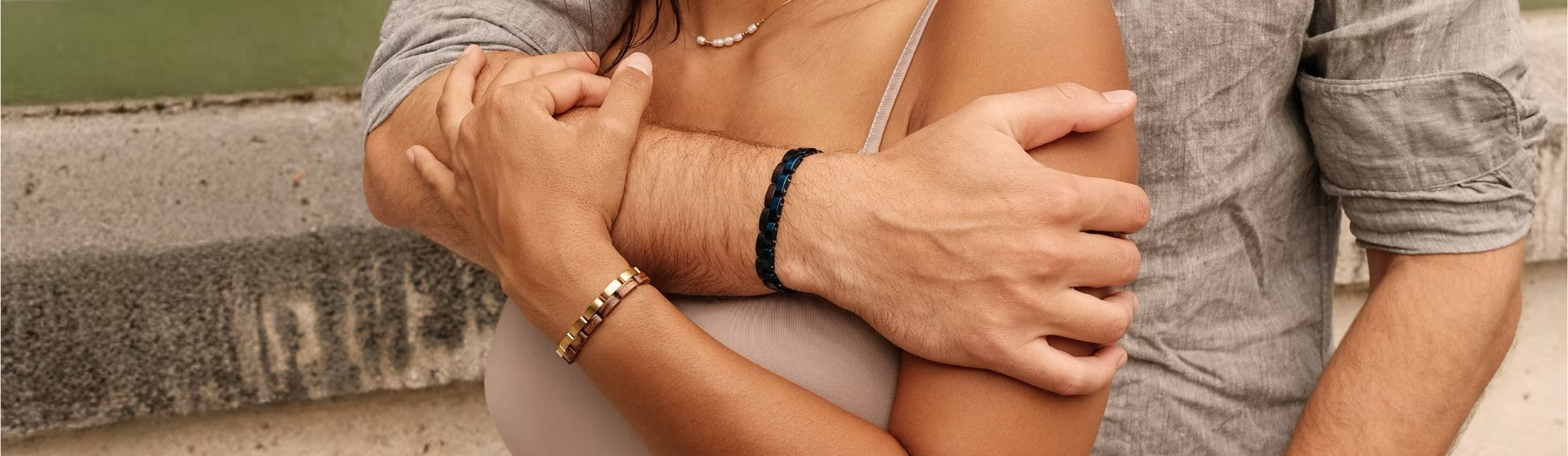 Couple wearing Aldoro wooden and metal bracelets, showcasing men’s and women’s luxury jewelry in a stylish, intimate setting.
